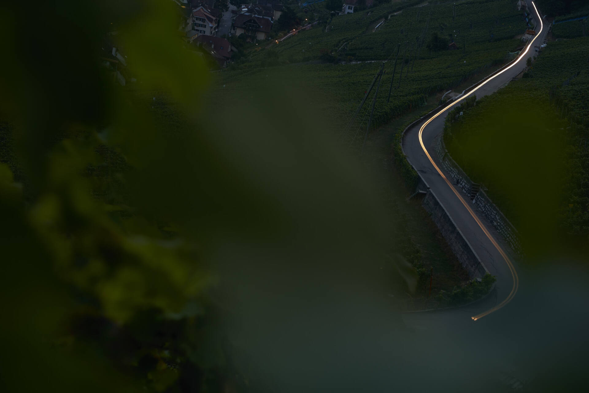 Dieselbe kurvige Strasse in der Dämmerung, ein dünner gelber Lichtstreifen folgt nun dem Verlauf der Fahrbahn.